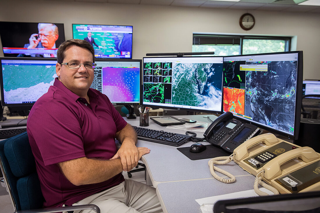 NOAA 기상 서비스 사무실 워크스테이션 앞에 있는 NOAA 기상학자의 이미지